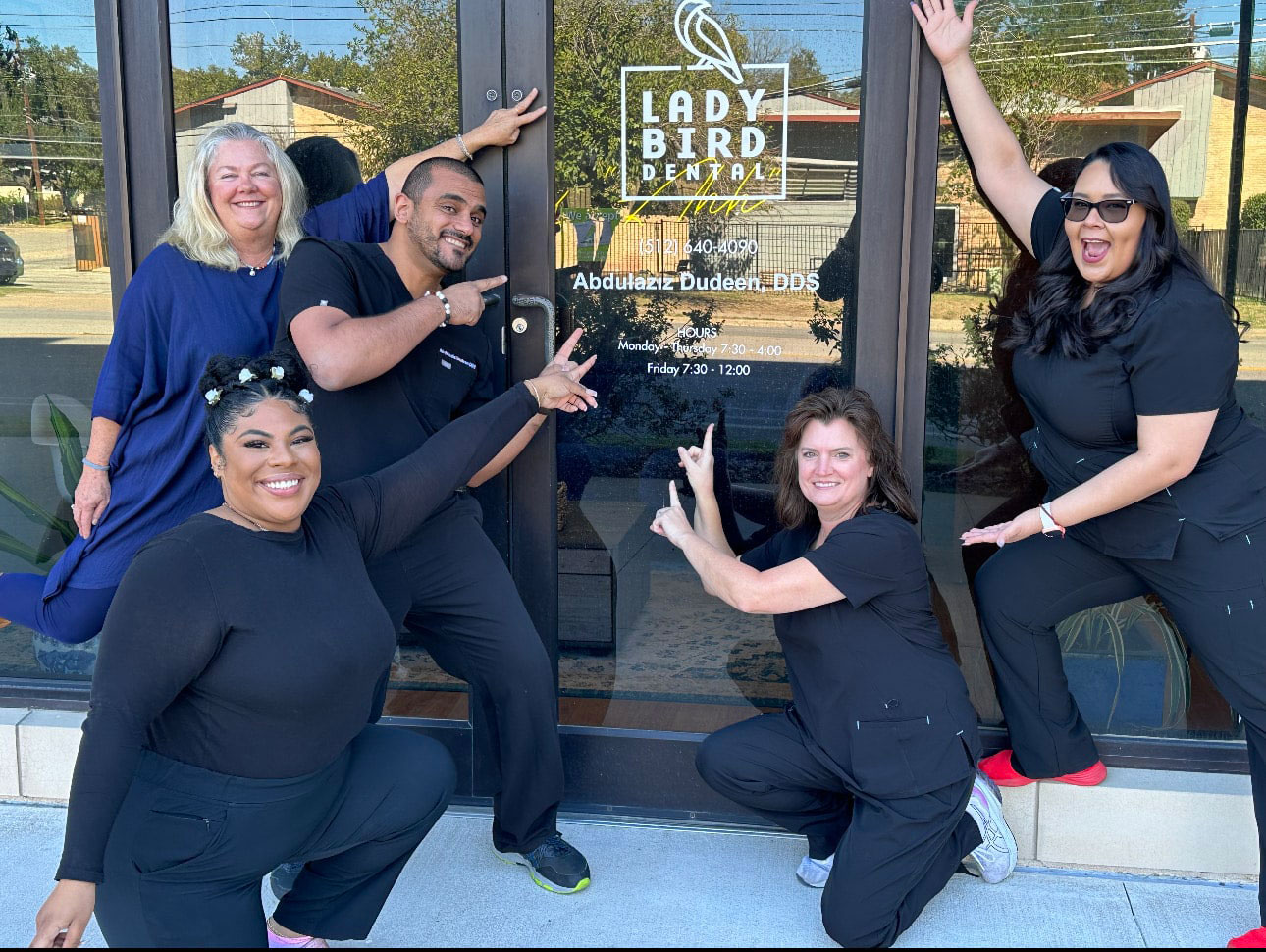 A group of people posing in front of a sign that reads Lady Bird Rehabilitation with a door behind them, suggesting they are promoting or celebrating the facility.