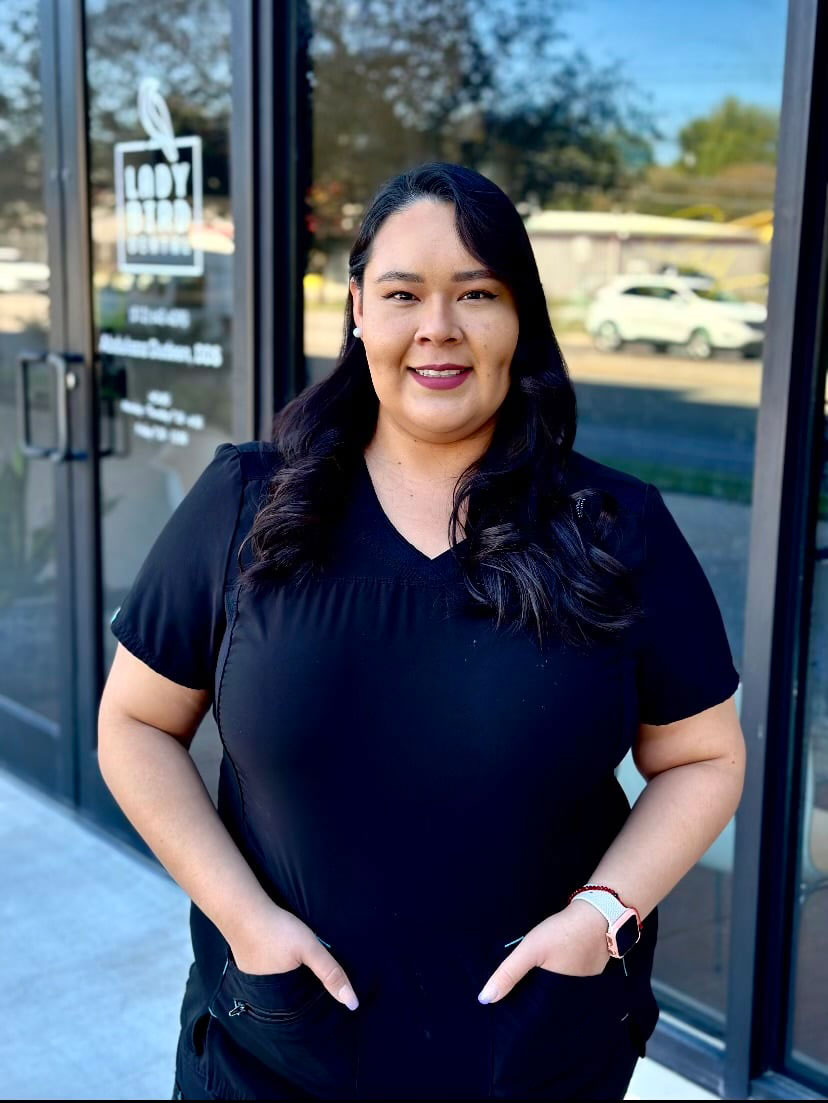 The image shows a person standing in front of a storefront with a smiling expression.